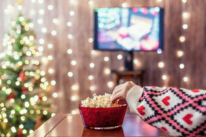 Christmas eve. Alone woman watching tv and eating popcorn. Home cinema. Cropped, close up